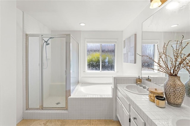 bathroom with a bath, double vanity, a shower stall, and a sink