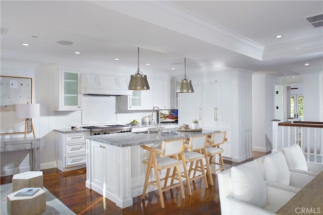 89 S La Senda Dr, Laguna Beach, CA 92651 - kitchen featuring visible vents, light stone counters, dark wood-style floors, ornamental molding, and custom range hood