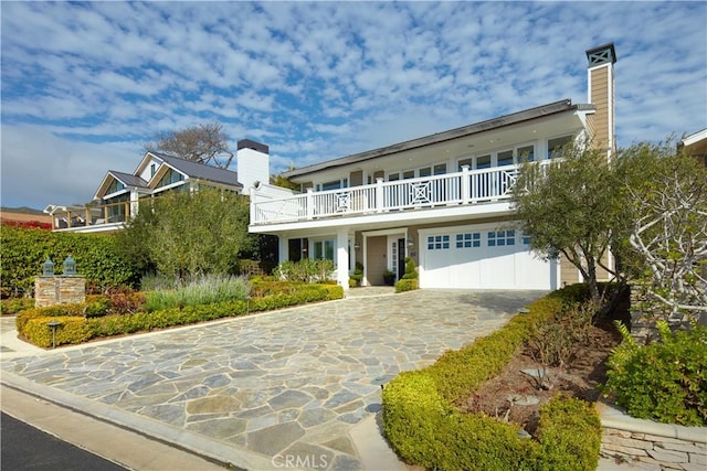 89 S La Senda Dr, Laguna Beach, CA 92651 - view of front of house featuring a garage, driveway, a balcony, and a chimney