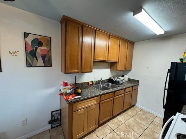 505 E Madison Ave Unit 84, El Cajon, CA 92020 - kitchen featuring dark countertops, brown cabinetry, freestanding refrigerator, and a sink