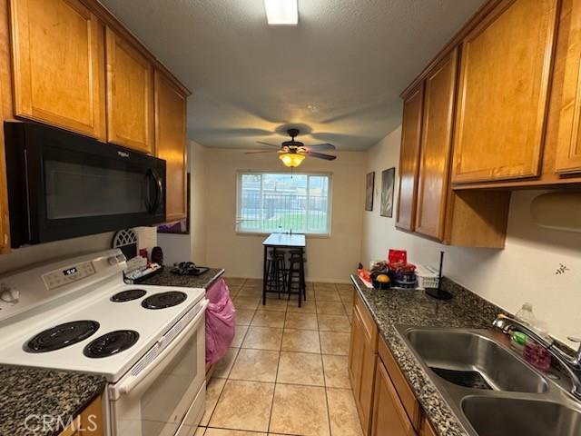 505 E Madison Ave Unit 84, El Cajon, CA 92020 - kitchen featuring white electric range, a sink, brown cabinetry, black microwave, and light tile patterned floors
