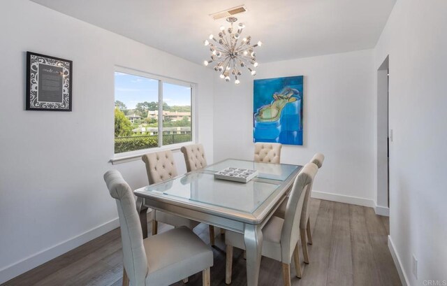 dining space featuring a chandelier, baseboards, and wood finished floors