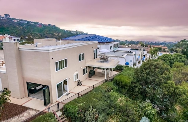 back of house with a patio area, stucco siding, and a balcony