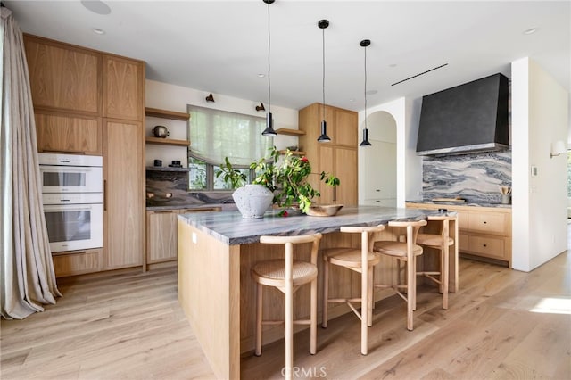 4209 Vantage Ave, Studio City, CA 91604 - kitchen featuring wall chimney range hood, open shelves, a kitchen island, light wood finished floors, and white double oven