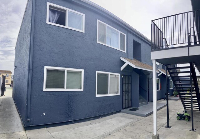 back of property with stucco siding, stairs, and a patio area