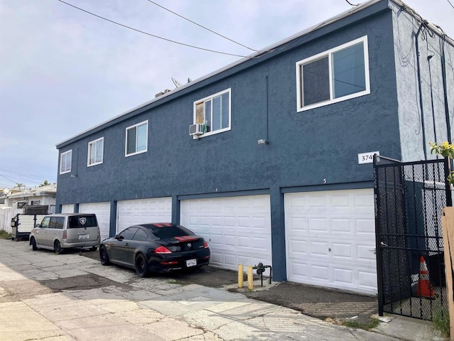 back of property with a garage, stucco siding, and fence