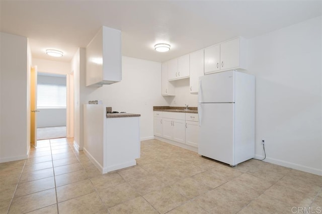 kitchen with white cabinetry, light tile patterned flooring, baseboards, and freestanding refrigerator