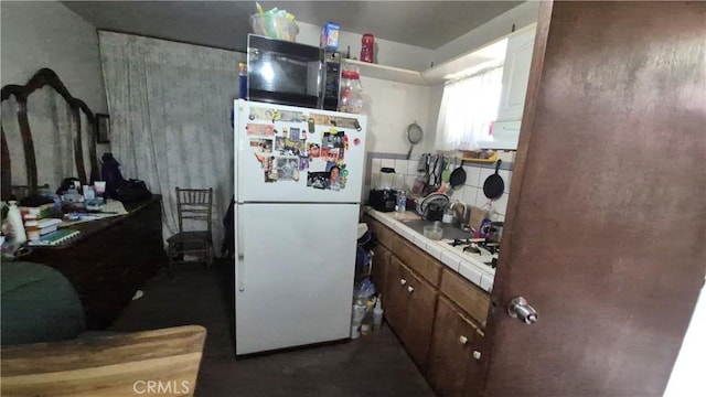 kitchen featuring freestanding refrigerator, a sink, tile countertops, and black microwave