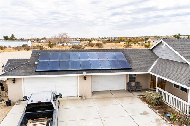 exterior space featuring solar panels, a garage, stucco siding, driveway, and roof with shingles
