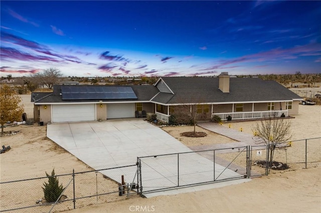 view of front facade featuring roof mounted solar panels, fence private yard, a porch, a gate, and concrete driveway