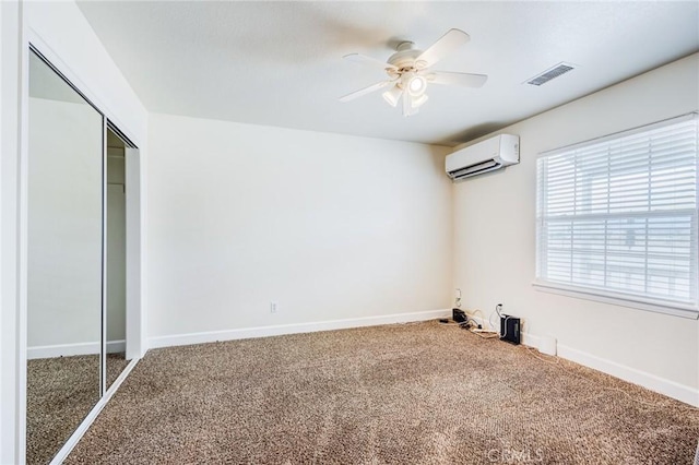 unfurnished bedroom with a wall unit AC, a closet, visible vents, carpet floors, and baseboards