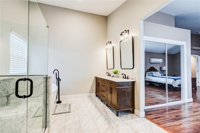 ensuite bathroom featuring baseboards, double vanity, a stall shower, a wall mounted air conditioner, and ensuite bathroom