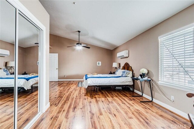 bedroom with light wood-style flooring, a wall unit AC, baseboards, and lofted ceiling