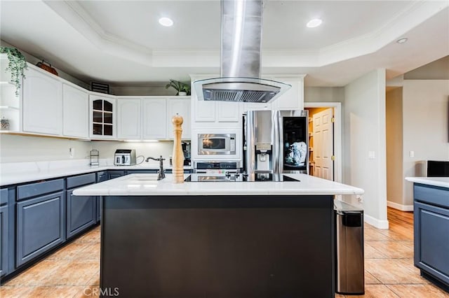 kitchen with island exhaust hood, light countertops, a tray ceiling, appliances with stainless steel finishes, and blue cabinets