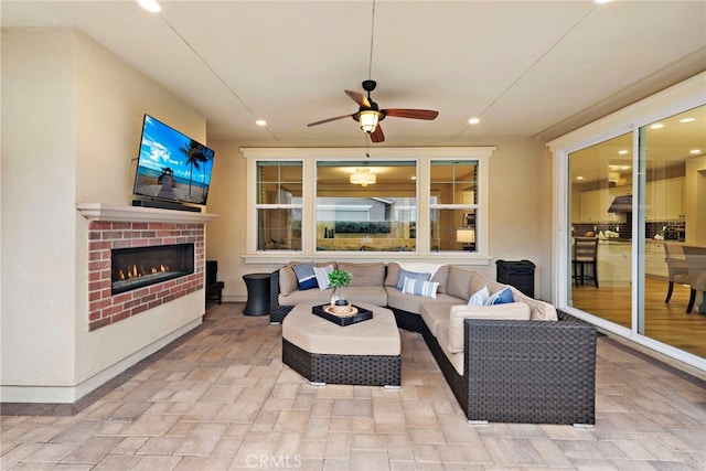 view of patio / terrace featuring an outdoor living space with a fireplace and a ceiling fan