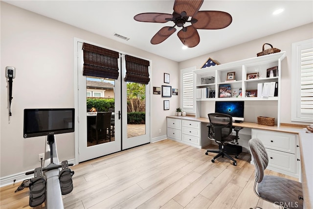 office area with visible vents, baseboards, built in desk, ceiling fan, and light wood-type flooring