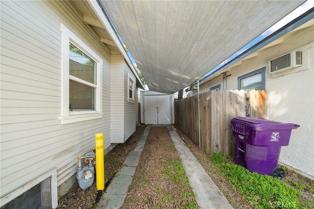 view of home's exterior featuring an outdoor structure, a storage unit, a wall mounted AC, and fence