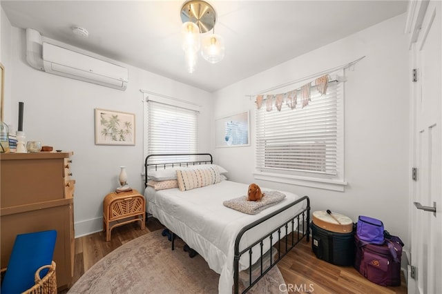 bedroom with wood finished floors and a wall unit AC