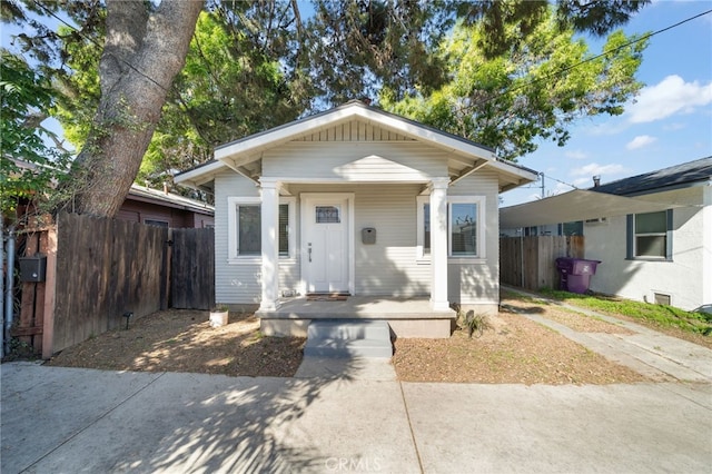 bungalow-style house with fence and covered porch