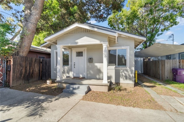 view of front of home featuring a porch, fence, board and batten siding, and a detached carport