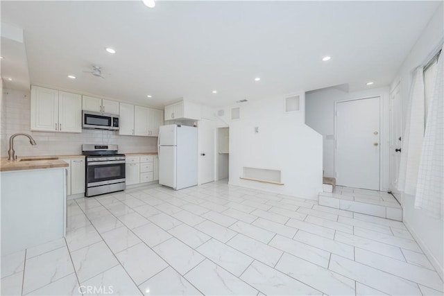 kitchen with recessed lighting, a sink, backsplash, and appliances with stainless steel finishes
