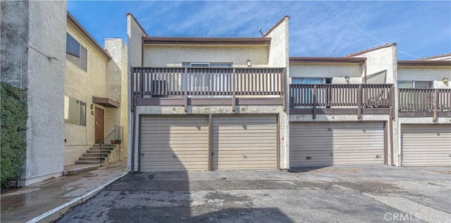 back of house featuring a garage, stucco siding, and aphalt driveway