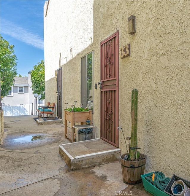 doorway to property featuring fence, a patio, and stucco siding