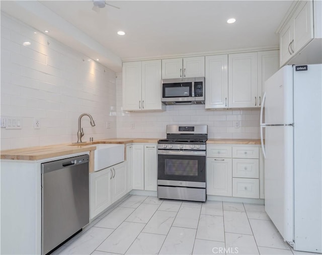 kitchen with light countertops, white cabinets, appliances with stainless steel finishes, marble finish floor, and a sink
