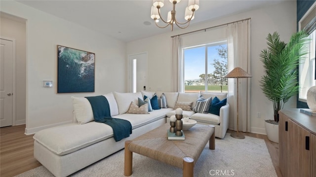 living room with light wood-style floors, baseboards, and a notable chandelier
