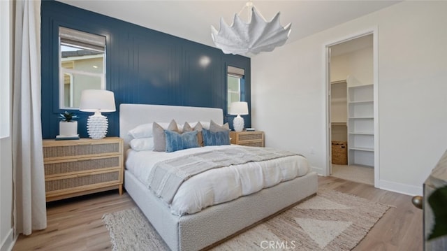 bedroom with baseboards, wood finished floors, and a spacious closet
