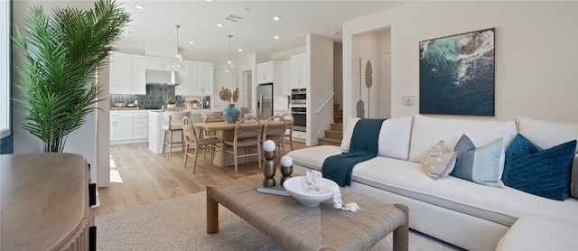 living room with visible vents, recessed lighting, stairs, and light wood-style floors