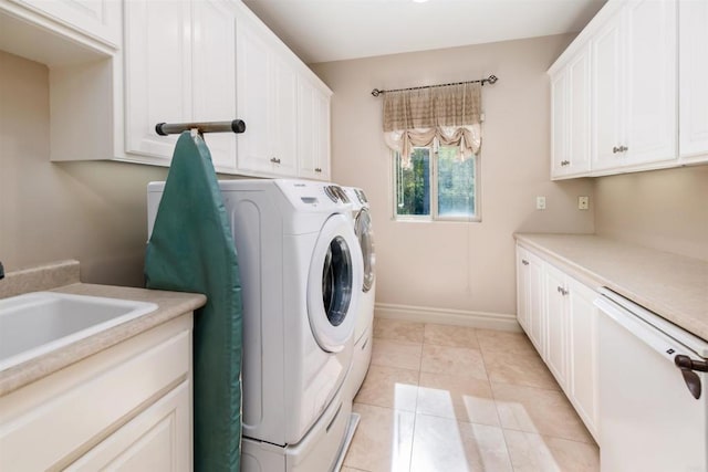 washroom featuring independent washer and dryer, a sink, cabinet space, light tile patterned flooring, and baseboards