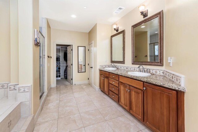 bathroom featuring double vanity, visible vents, a shower stall, and a sink