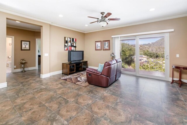 living area featuring baseboards, ornamental molding, and a ceiling fan