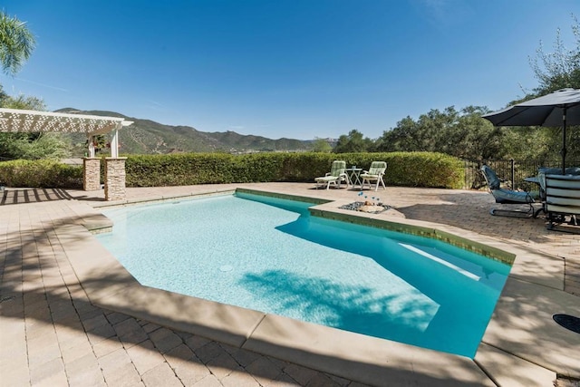 view of swimming pool featuring a fenced in pool, fence, a mountain view, a pergola, and a patio