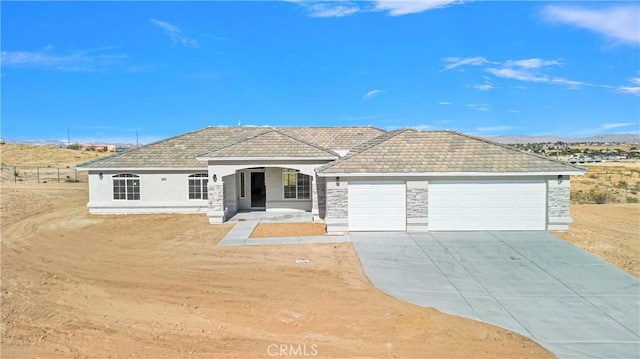 ranch-style home with stone siding, stucco siding, concrete driveway, and a garage