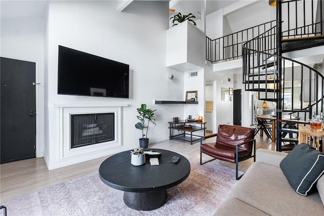 living area with stairway, wood finished floors, baseboards, and a towering ceiling