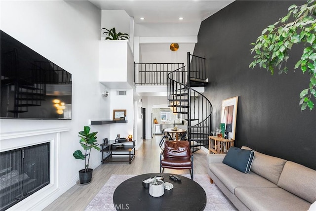 living room featuring visible vents, wood finished floors, stairway, a high ceiling, and baseboards