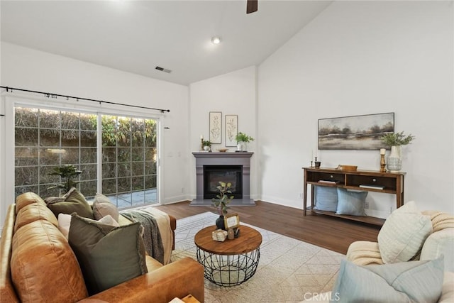 living area with visible vents, high vaulted ceiling, baseboards, and wood finished floors