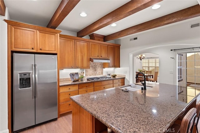kitchen with visible vents, under cabinet range hood, a sink, stainless steel appliances, and arched walkways