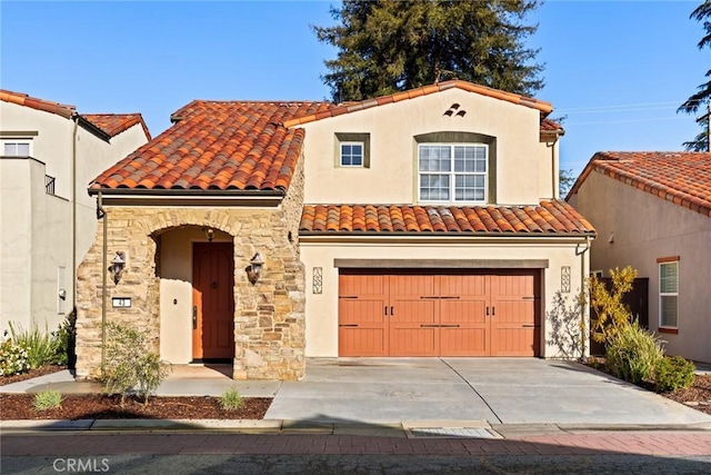 mediterranean / spanish house with stucco siding, a tile roof, stone siding, concrete driveway, and a garage