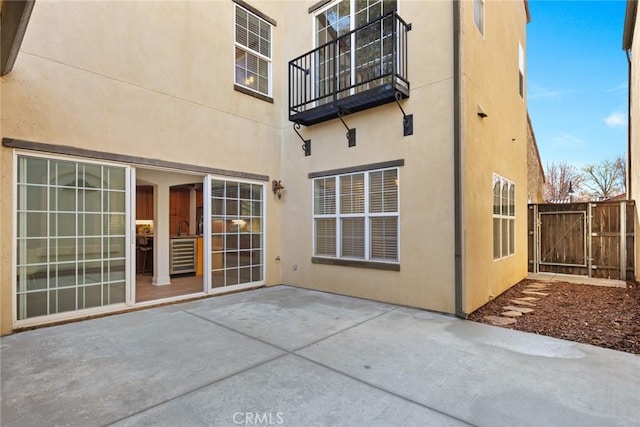 rear view of house with a gate, stucco siding, a patio, and fence