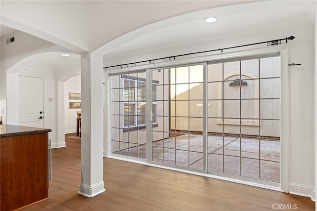 interior space with arched walkways, visible vents, baseboards, and wood finished floors