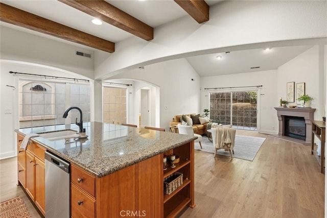 kitchen with visible vents, a sink, stainless steel dishwasher, open floor plan, and arched walkways