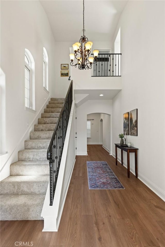 entryway with arched walkways, stairs, a wealth of natural light, and wood finished floors