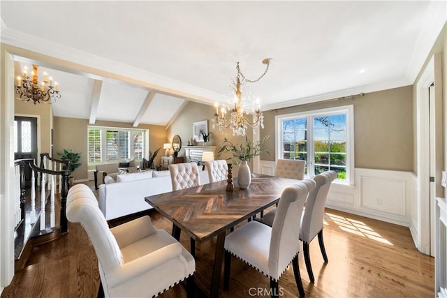dining room with a wainscoted wall, vaulted ceiling with beams, wood finished floors, and an inviting chandelier