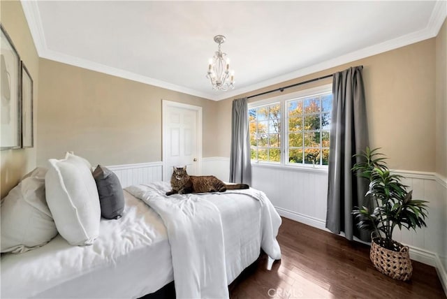 bedroom with an inviting chandelier, a wainscoted wall, crown molding, and dark wood finished floors
