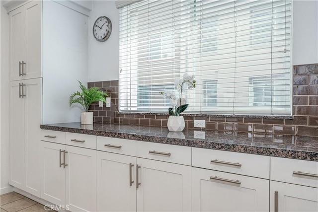 kitchen featuring tasteful backsplash, white cabinets, and dark stone countertops
