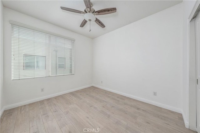 spare room featuring light wood finished floors, baseboards, and a ceiling fan