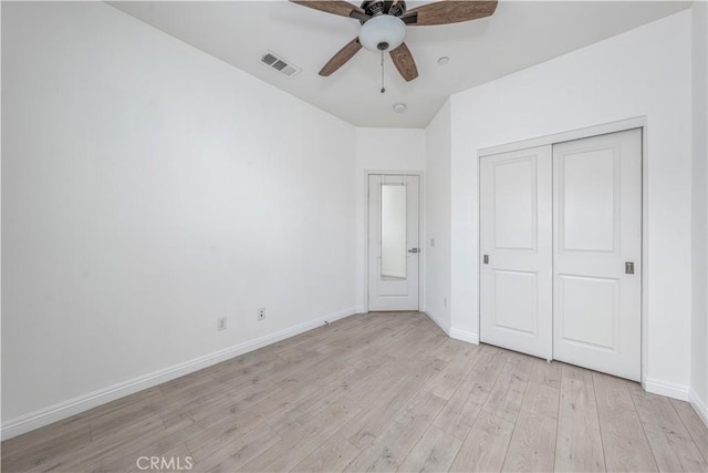 unfurnished bedroom featuring light wood finished floors, baseboards, a closet, vaulted ceiling, and a ceiling fan